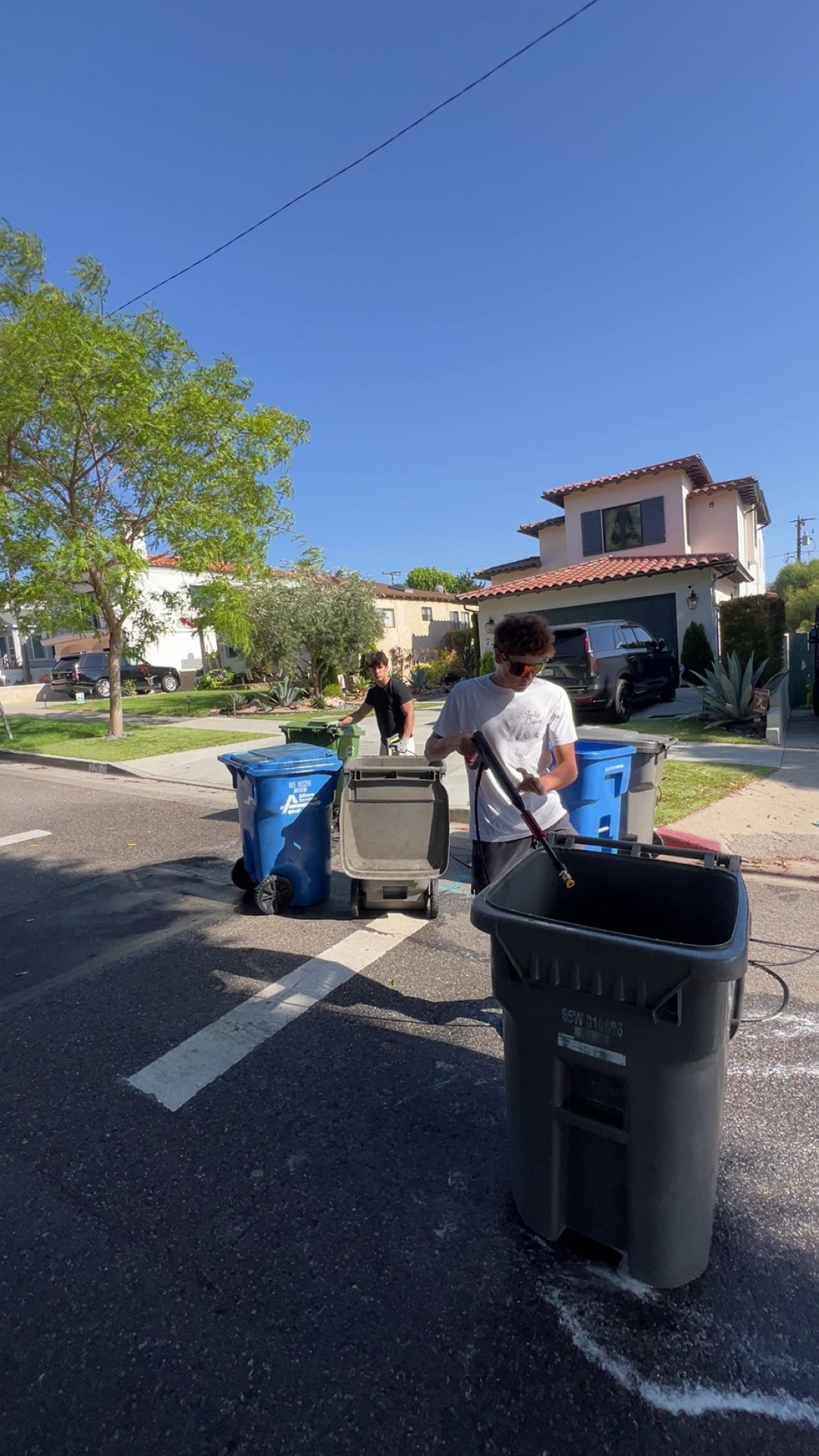 Trash bin washing service — multiple bins being cleaned in the street